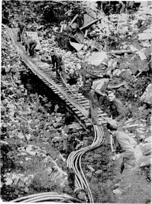 Sport and General" Photo. Repairing London's bombed telephone system. A Post Office engineering emergency squad getting telephone cables into place across a large bomb crater by means of a temporary bridge. Each of these cables carries hundreds of separate telephone circuits. (Evening Post, 26 November 1940)