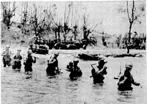Carrying weapons and ammunition, American soldiers wade through a stream on Manus, one of the Admiralty Islands. In the background are two caterpillar tractors pulling trailers. (Evening Post, 16 May 1944)