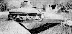 U.S. Office of War Information Photo. A deep ditch in Italy being crossed by an American tank, travelling over a bridge laid by an army tractor. (Evening Post, 04 July 1944)