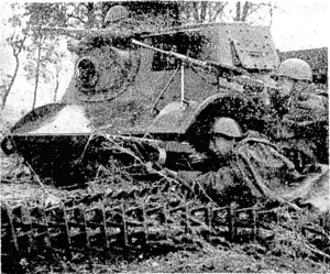 Red Army soldiers, in the shelter of a small German tank which they had captured, fire at the enemy in the Vitebsk area. (Evening Post, 05 July 1944)