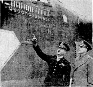 Colonel Leon W. Johnson, awarded the United States Medal of Honour, equivalent to the British V.C., for gallantry during the famous American raid on the Ploesti oilfields, in Rumania, shows General Devers a decoration on a Liberator which participated in the raid. The bomb lying on its side represents Ploesti, where the bombers flew so low that the bombs were placed, not dropped, on. the target. (Evening Post, 15 February 1944)