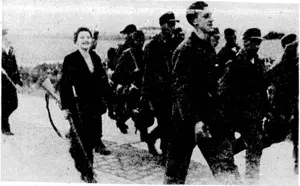 A woman of the Belgian Resistance Movement acts as escort to German prisoners of war being marched into captivity in the vicinity of Brussels. . (Evening Post, 13 October 1944)