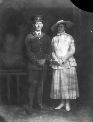 Man in military uniform with a woman dressed in a suit and hat