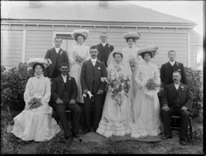 Unidentified wedding group, showing bride and groom, groomsmen, bridesmaids and [father of bride?] outside wooden house, probably Christchurch district