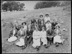 Group of young men and women, sitting on a grassy hillside, probably Christchurch district