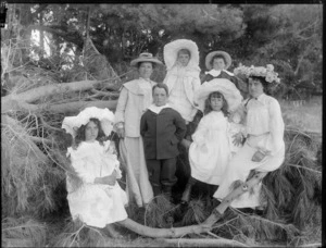 Unidentified group of women and children outdoors, sitting in the branches of a fallen pine tree, probably Christchurch district