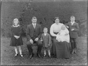 Unidentified family group, outside with hedge behind, probably Christchurch district