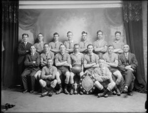 Studio portrait of Woolston Junior Rugby League Football team, Christchurch, including shield and cup trophy, probably Christchurch district