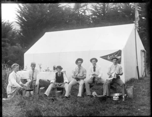Unidentified young men doing domestic chores next to tent 'Lily', at camp site, probably Sumner, Christchurch district