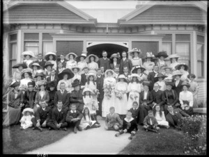 Unidentified bride and groom with wedding party, family and friends, in front of house, probably Christchurch district