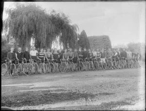 Group of unidentified cyclists standing in a row on an unidentified street, probably Christchurch district