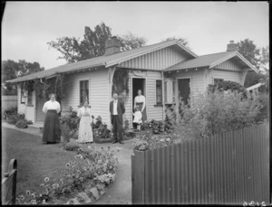 Exterior view of a house, showing unidentified family and garden, probably Christchurch district