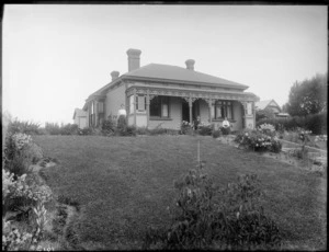 Unidentified man and women outside of house, in front of garden, probably Christchurch district