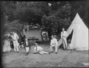 Group of five unidentified men at a Royal Mountaineers camp, shows two men holding rifles and one standing next to a Penny Farthing bicycle, with a tent on the right and dead rabbits hung up in the background, probably Christchurch district