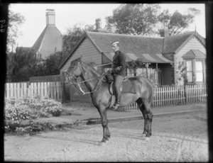 Unidentified mounted rider from Canterbury Mounted Rifles, with house behind, probably Christchurch district