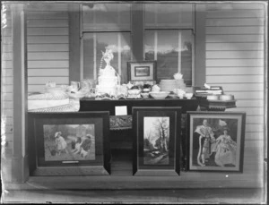 Wedding presents, pictures, fine china and wedding cake on show on the veranda of a house, probably Christchurch region