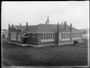 Large single story brick building with large windows, a steeple on roof and lawn foreground, Somerfield School, Christchurch