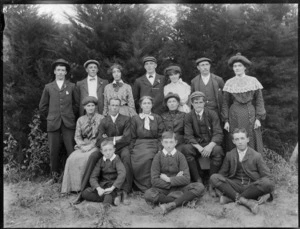 Group portrait in front of trees, unidentified older woman with extended family, younger men and women with young boys in front, probably Christchurch district