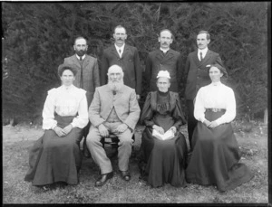 Group portrait, unidentified elderly couple with their adult family members,four men and two woman, hedge beyond, probably Christchurch region