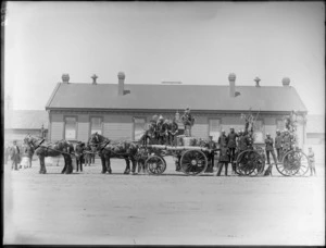 Christchurch Railways Volunteer Fire Brigade [float?], unidentified men in dress uniforms, hats and medals, horse drawn wagons carrying fire fighting equipment decorated in foliage, Railways depot behind