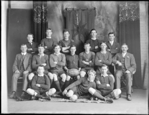 Studio portrait of the Hornby League Football Team of 1914-15, unidentified players in uniforms and coaches, Hornby Pennant hanging behind, Christchurch