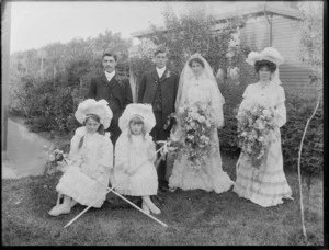 Unidentified bride and groom with best man, bridesmaid and flower girls, in garden next to house, probably Christchurch district