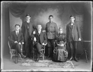 Studio family portrait with unidentified older parents and their four adult sons, youngest son in soldier's uniform standing between twin brothers, Christchurch