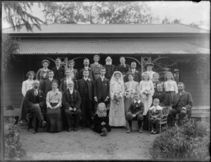Unidentified wedding group, showing bride and groom, wedding party and family members outside a house, probably Christchurch district