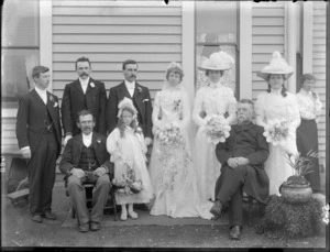 Unidentified wedding group, shows bride and groom and wedding party outside a wooden house, probably Christchurch district