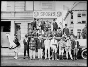 Group of unidentified men and women in costume, on and alongside a truck [parade float?], with a sign saying '9 Sports 9', probably Christchurch district