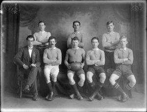Studio portrait of an unidentified men's Rugby League Football team, with coach wearing rosette, probably Christchurch district