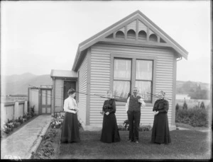 Unidentified man and three women, all mature in age, outside a single storied wooden house, probably Christchurch district