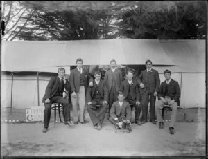 Group of young men with dog outside tent, sign says 'Tivoli Camp', Sumner, Christchurch