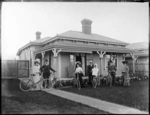 Group of unidentified men, women and child with bicycles in front of house, probably Christchurch region