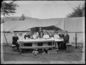 Group of men and women including a child and two dogs having a meal outside 'Imperial Camp' tents, Sumner, Christchurch