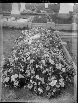 Grave plot covered with flowers, unidentified graves with headstones beyond, Christchurch