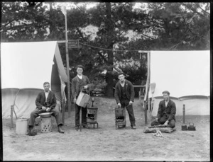 Group of unidentified men outside tents, each man performing a domestic duty, includes sign reading 'Myrtle Camp', [New Brighton, Christchurch district?]