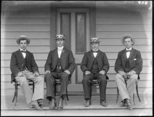 Group of unidentified men, all of whom wear business attire, and wear straw boaters, sitting in bentwood chairs on the vendandah of a wooden house, Christchurch district