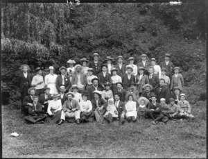Large group, including men and women who have swapped hats with each other, and children, in an outdoor location, possibly Christchurch district