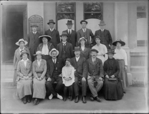 Group portrait of unidentified men and women in hats with young girl, outside the Orange Hall building of the Loyal Orange Institution charitable organisation, Christchurch District Number 5, probably Christchurch region