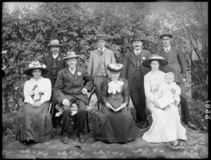 Family group, showing unidentified men and women, one holding a baby, in a garden, possibly Christchurch district