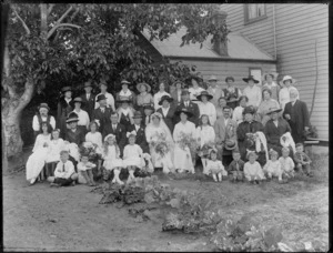 Wedding group, showing unidentified men, women and children, in a garden with a vegatable patch in foreground, possibly Christchurch district