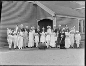Group in fancy dress, showing unidentified men, women amd children dressed as royalty, outside a wooden [hall?] building, possibly Christchurch district