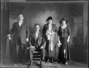 Studio portrait of a [wedding?] group, showing two men and two women, all unidentified, one of the women holds a bouquet of flowers, Christchurch