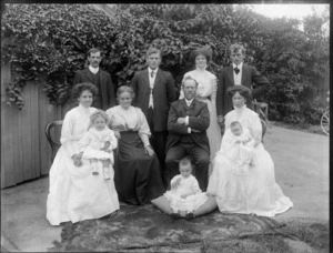 Family group, showing unidentified men, women and children, with creeper on wall behind, possibly Christchurch district