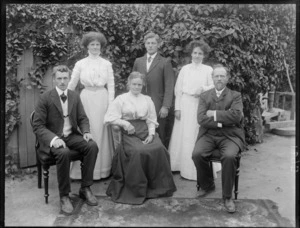 Family group, showing unidentified men and women, with creeper on wall behind, possibly Christchurch district
