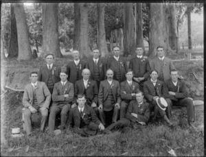 Group of indentified men, all wearing business attire, each with a small rosette pinned to their lapel, in an outdoor location, possibly Christchurch district