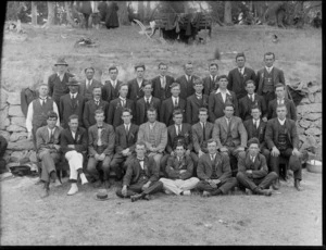 Large group of men, some wear a small rosette pinned to lapel, in an outdoor location, possibly Christchurch district