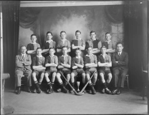 Unidentified group of schoolboy hockey team members and coaches, showing a cup and hockey sticks, taken in the studio, probably Christchurch district