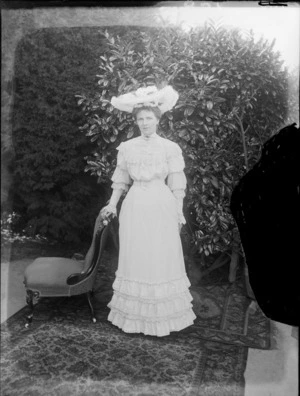 Unidentified woman standing next to a chair, taken in the garden, possibly Christchurch district